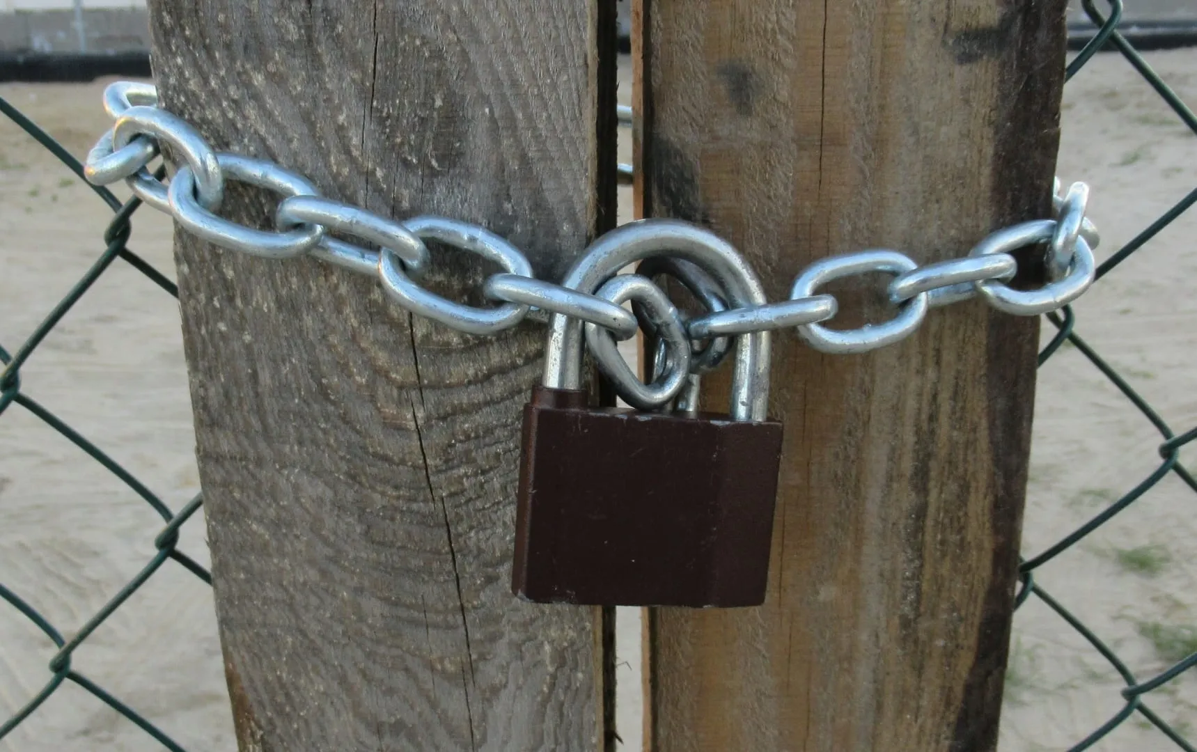 Un cadenas et une chaîne fermant un portail en bois